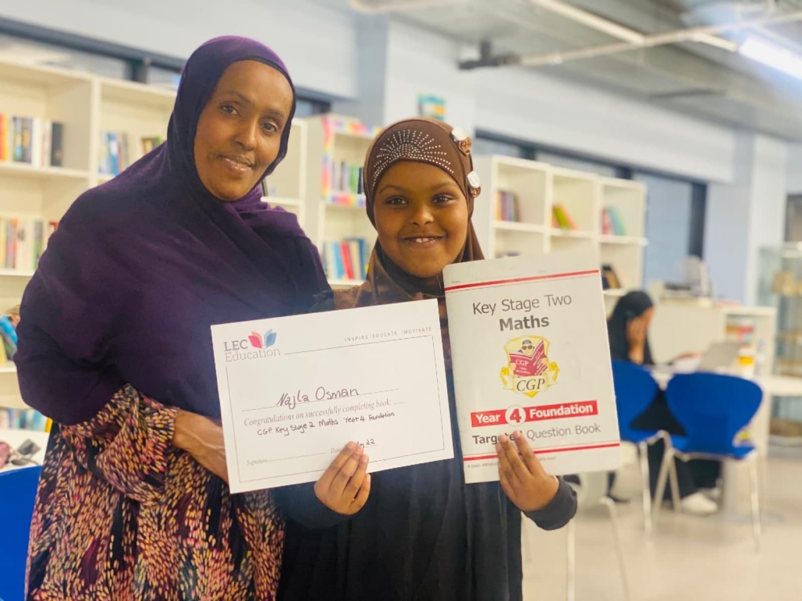 Student and mentor celebrating a completed Maths book at LEC